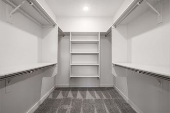 A long, narrow walk-in closet with shelves and a carpeted floor.